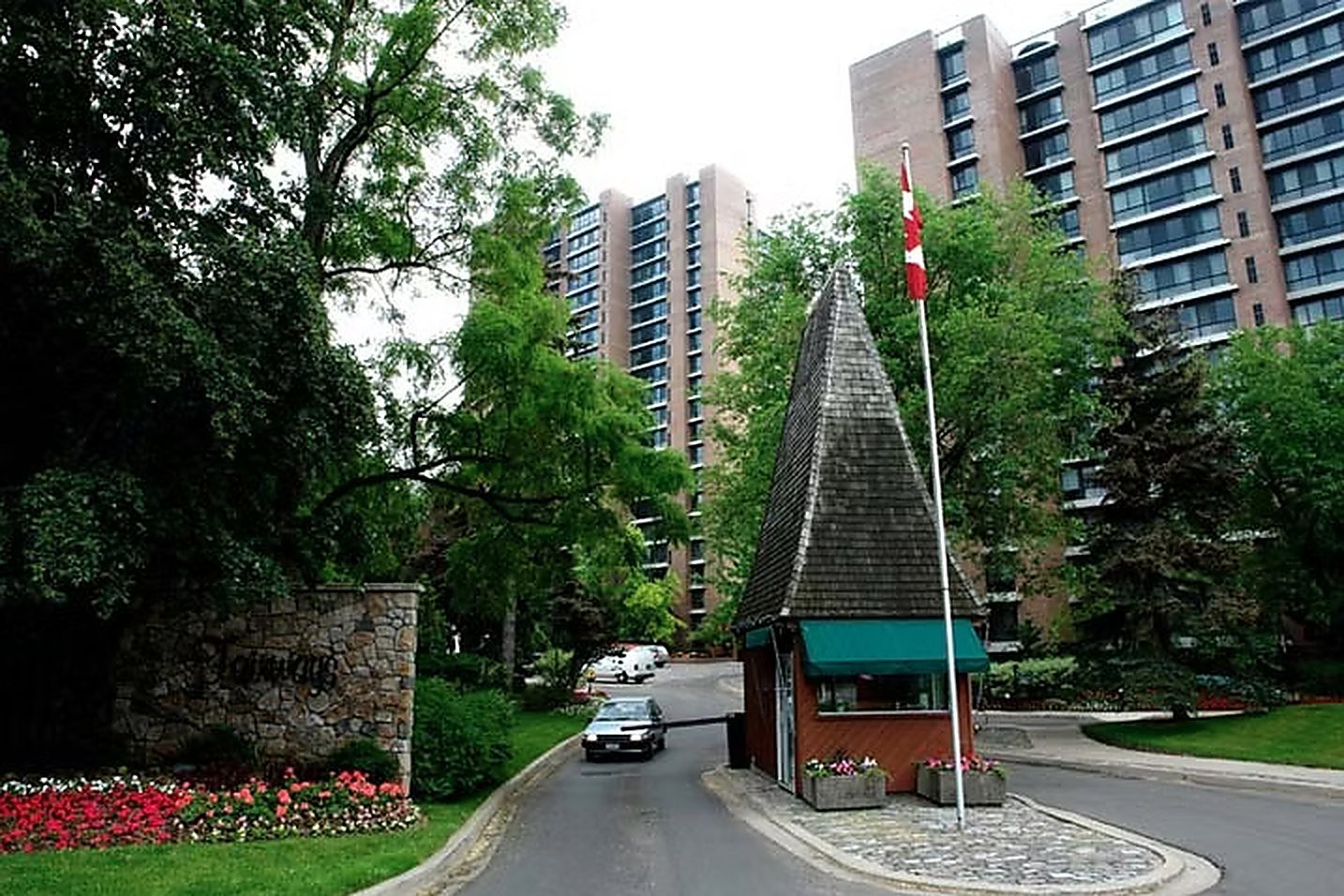 The gatehouse at the Fairways entrance with its shingled peaked roof, Canadian flag and stone entrance wall