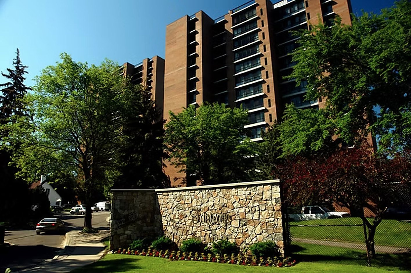 The Fairways stone entrance wall with the building rising behind mature trees