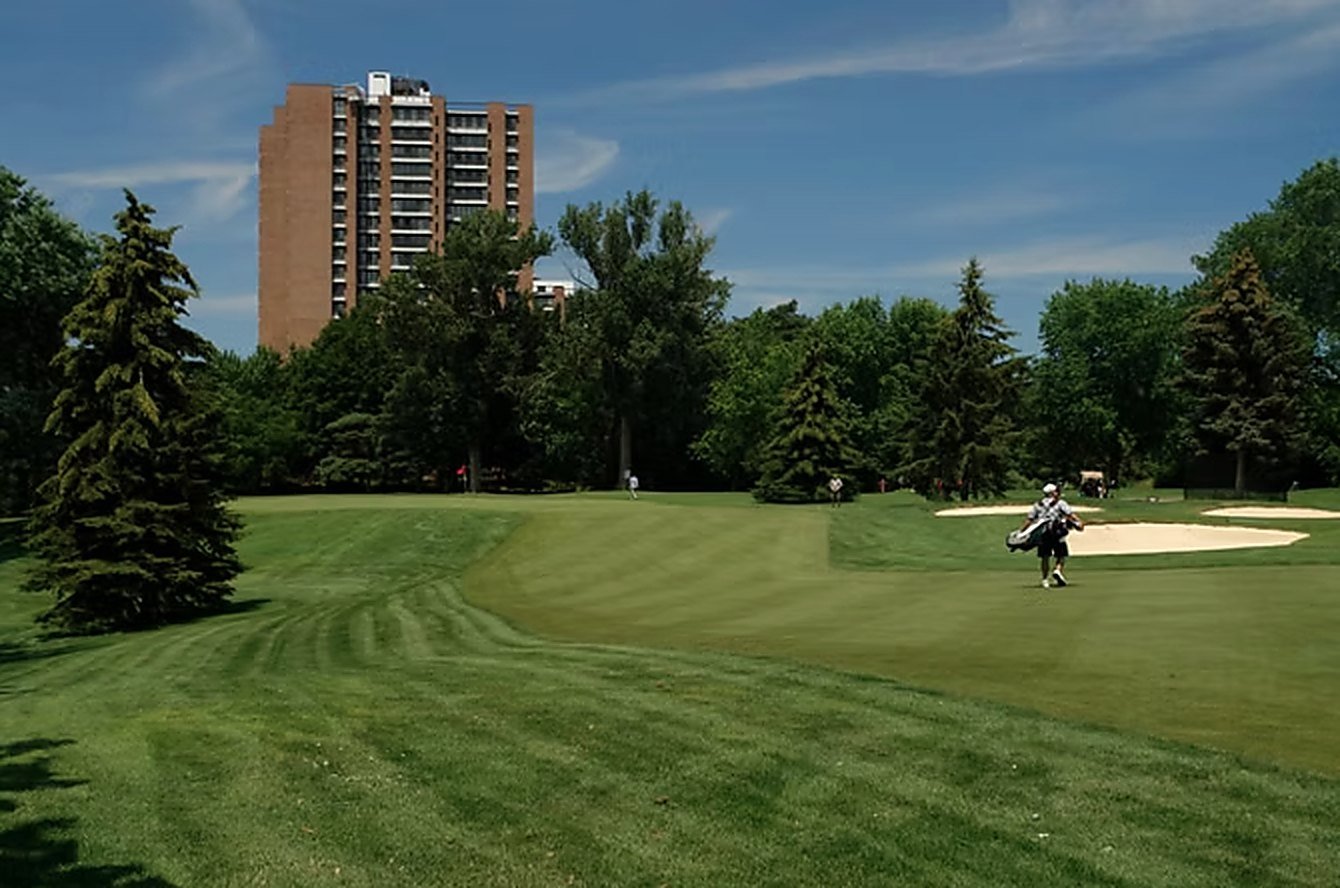 The Fairways tower rising above mature trees at the edge of an adjacent golf course fairway