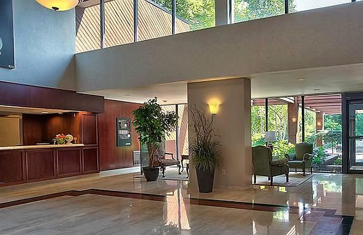 The double-height lobby with travertine floors, wood reception desk and garden outlook